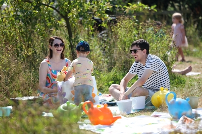 Family sitting on a blanket eating food on a sunny day