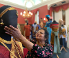 Smiling woman altering the figure of a mannequin wearing a dress.