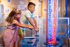 Two children pressing down on a thin metal bar to interact with an exhibition
