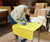 Lady with gloves on and a cloth cleaning a table.