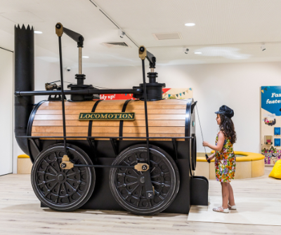 Young girl interacting with a model Locomotion train. 