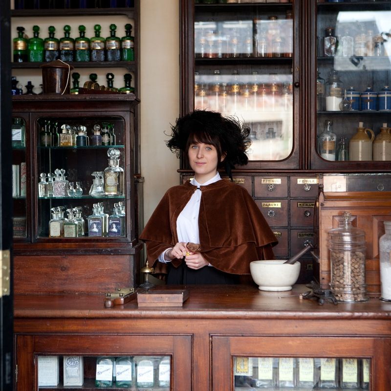 Chemist On The Victorian Street Costumed interpreter dressed in Victorian dress behind the counter in the Chemist shop on the Victorian Street