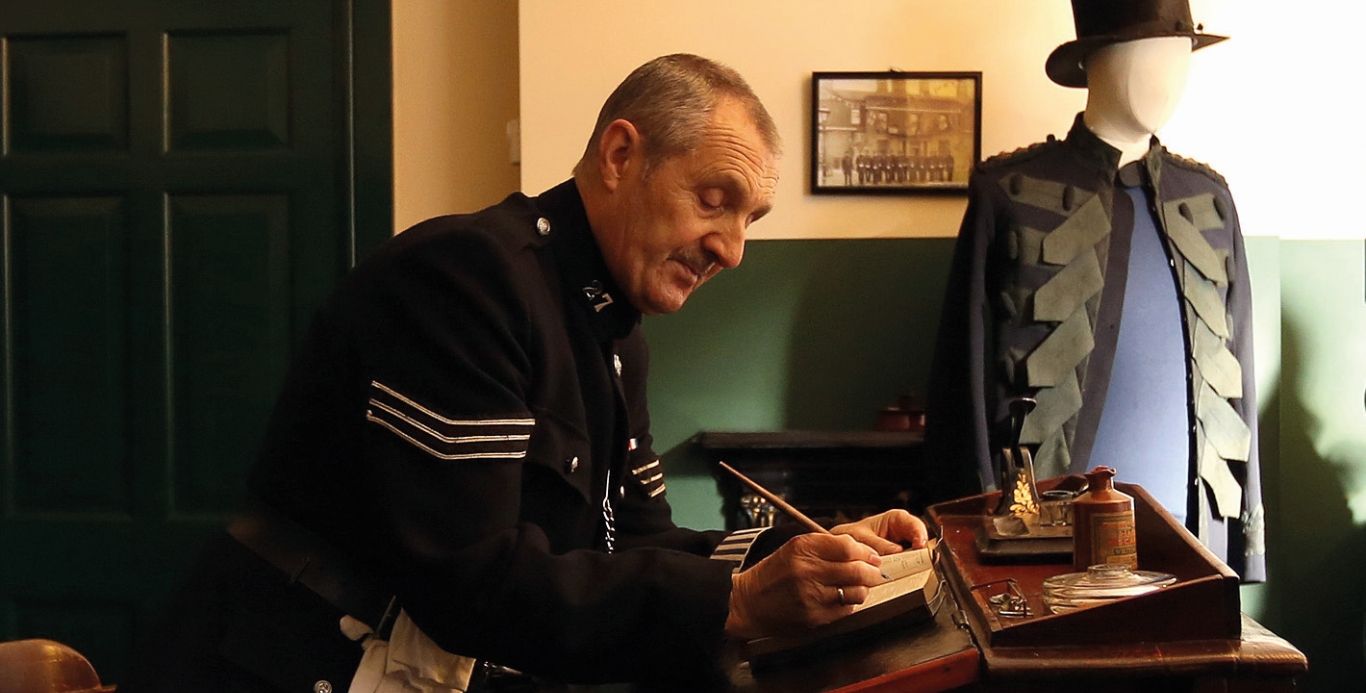 Costumed interpreter dressed as a Victorian police man working in the police station