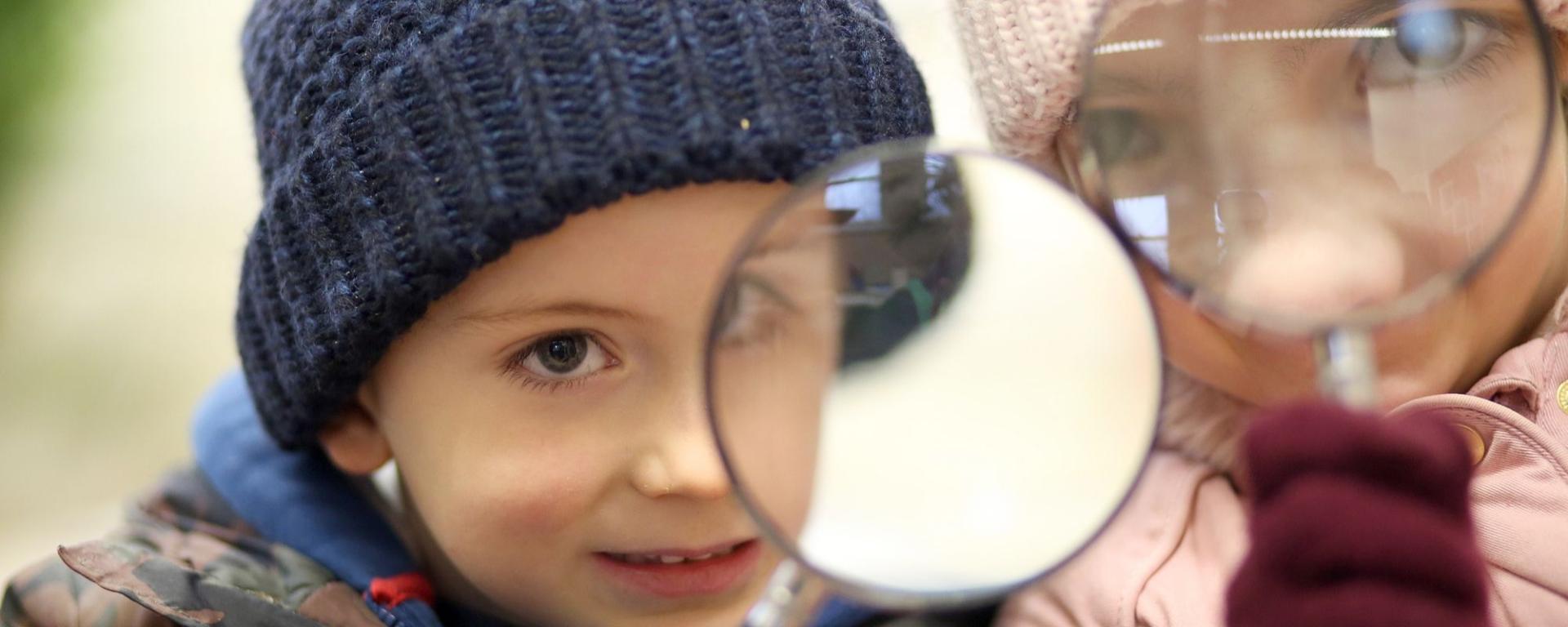 Young Boy And Girl Looking Through A Magnifying Glass Young Boy And Girl Looking Through A Magnifying Glass
